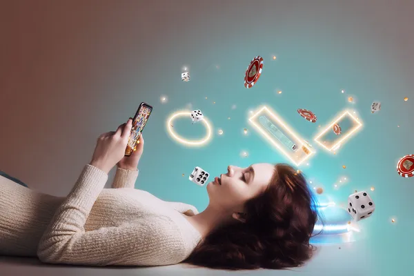 A young woman relaxing with her phone while dynamic casino elements float around her, illustrating the smooth mobile experience offered by the PHCHARMS app.