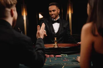 A professional dealer in a tuxedo greeting players at the roulette table, symbolizing the authentic live casino feel at PHCHARMS.