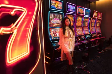 A stylish woman beside vibrant slot machines displaying glowing sevens, showcasing the variety of top slots at PHCHARMS.