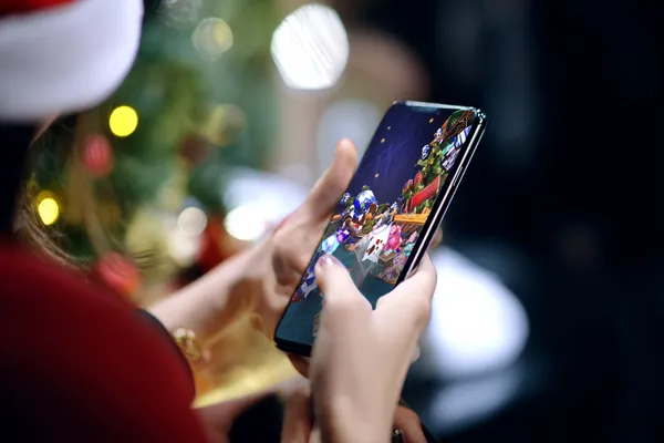 A player using their smartphone during a festive local event, representing PHCHARMS’s fully mobile-friendly casino.