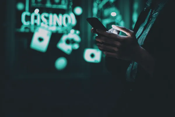 A person using their device against a moody casino-themed background, illustrating the smooth re-entry process at PHCHARMS.